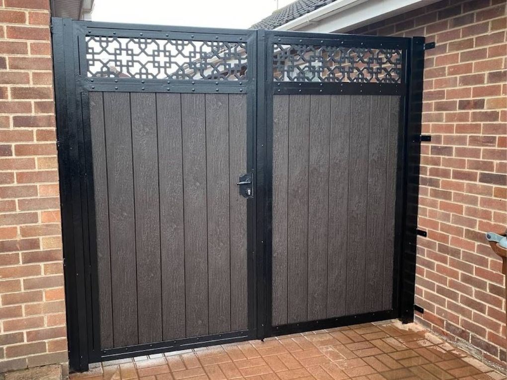 Pair of dark composite gates with laser-cut trellis top panels between brick walls