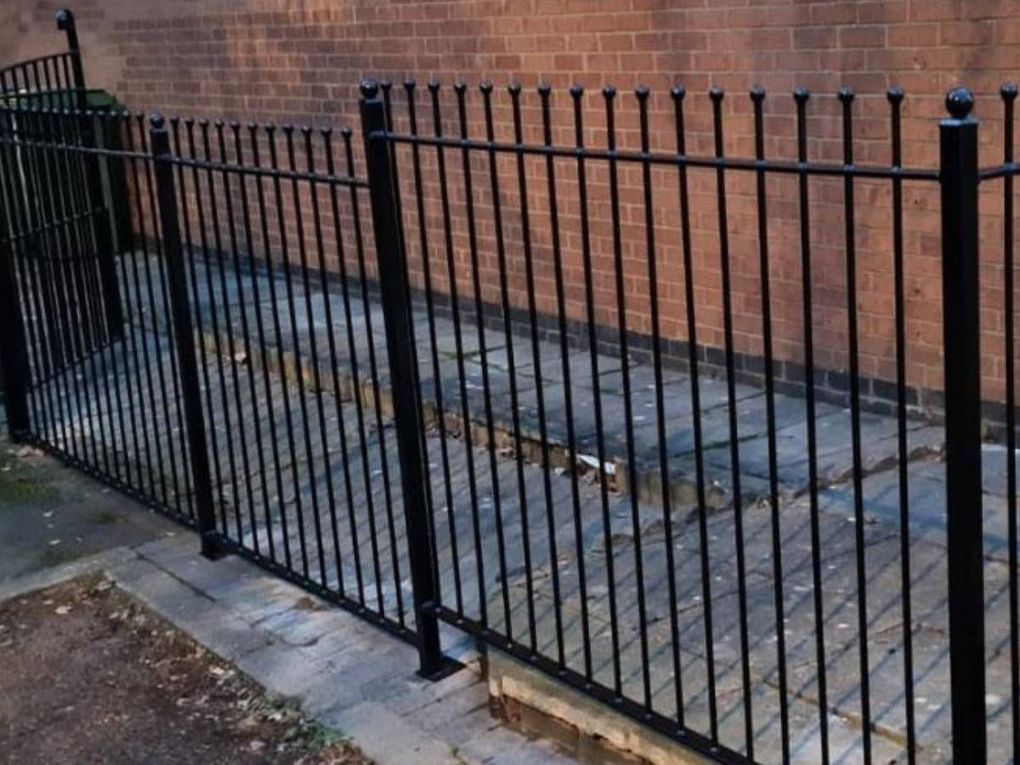 Run of black ball-top railing fence along a paved side path