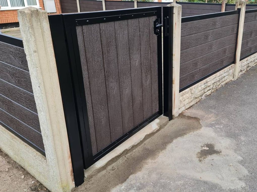 Low composite front garden gate in a black frame, matching composite fencing alongside