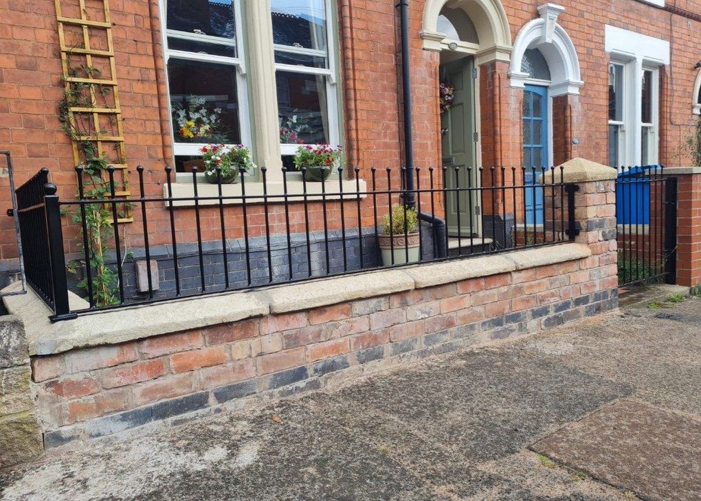 Black ball-top railings fitted along the stone coping of a Victorian terrace's front garden wall