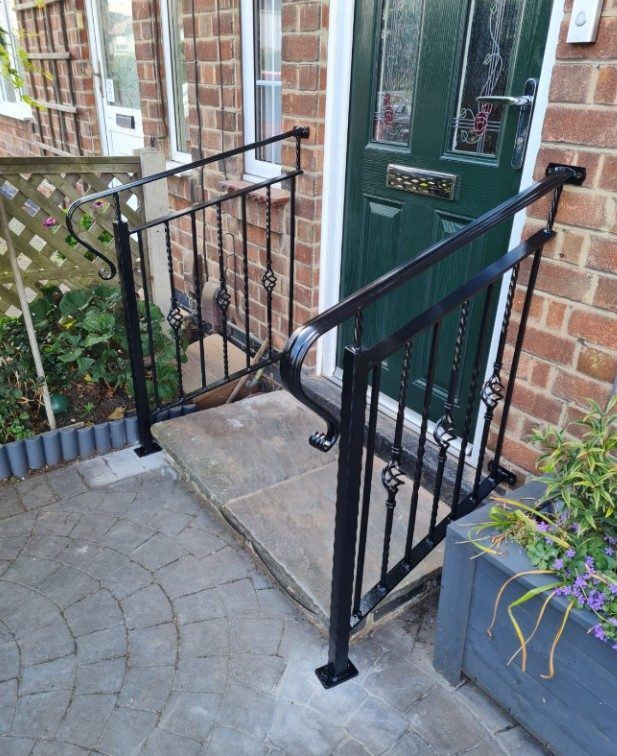 Black handrails with twisted spindles and scrolled ends either side of a front doorstep