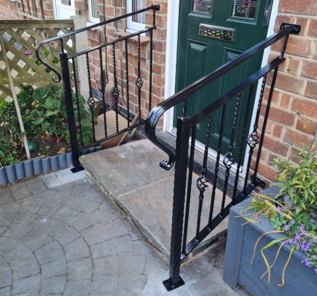 Black metal handrails with twisted spindles either side of a front doorstep