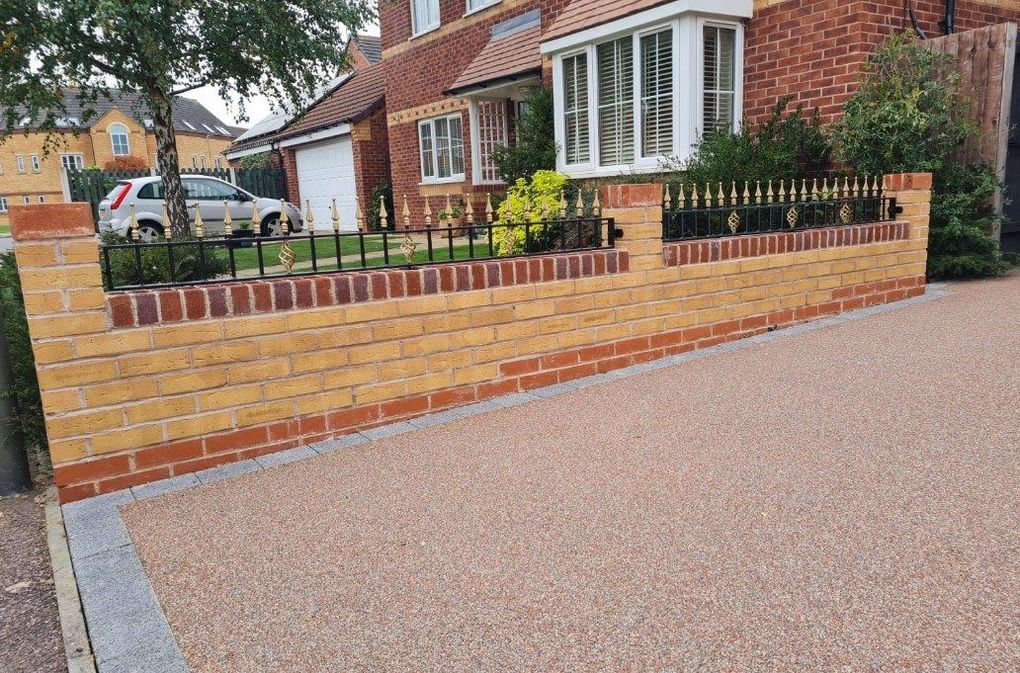 Black railings with gold finials along a new brick garden wall