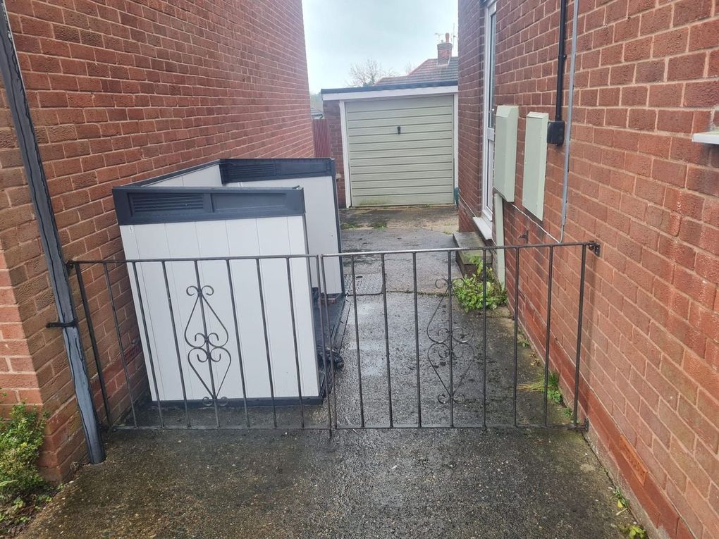 Old black metal gate with worn paint across a side passage between two houses