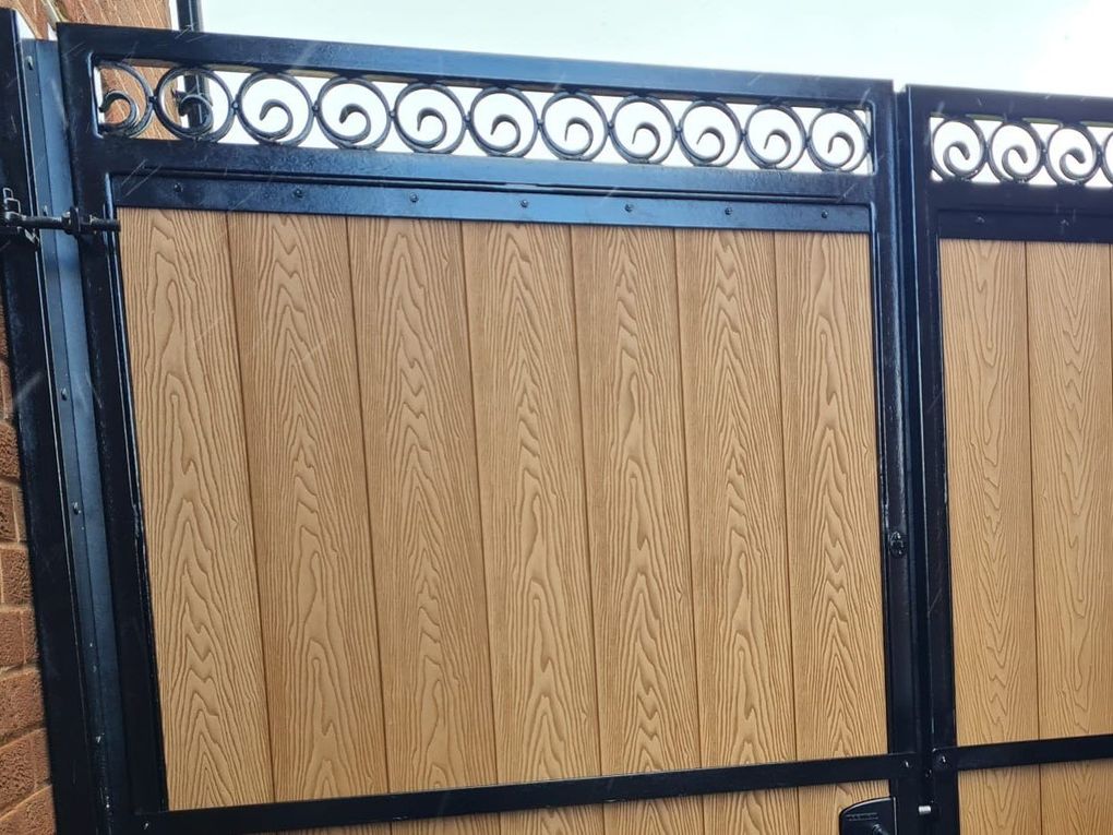 Close-up of black C-scrolls welded in a row to form the top rail of a pair of gates