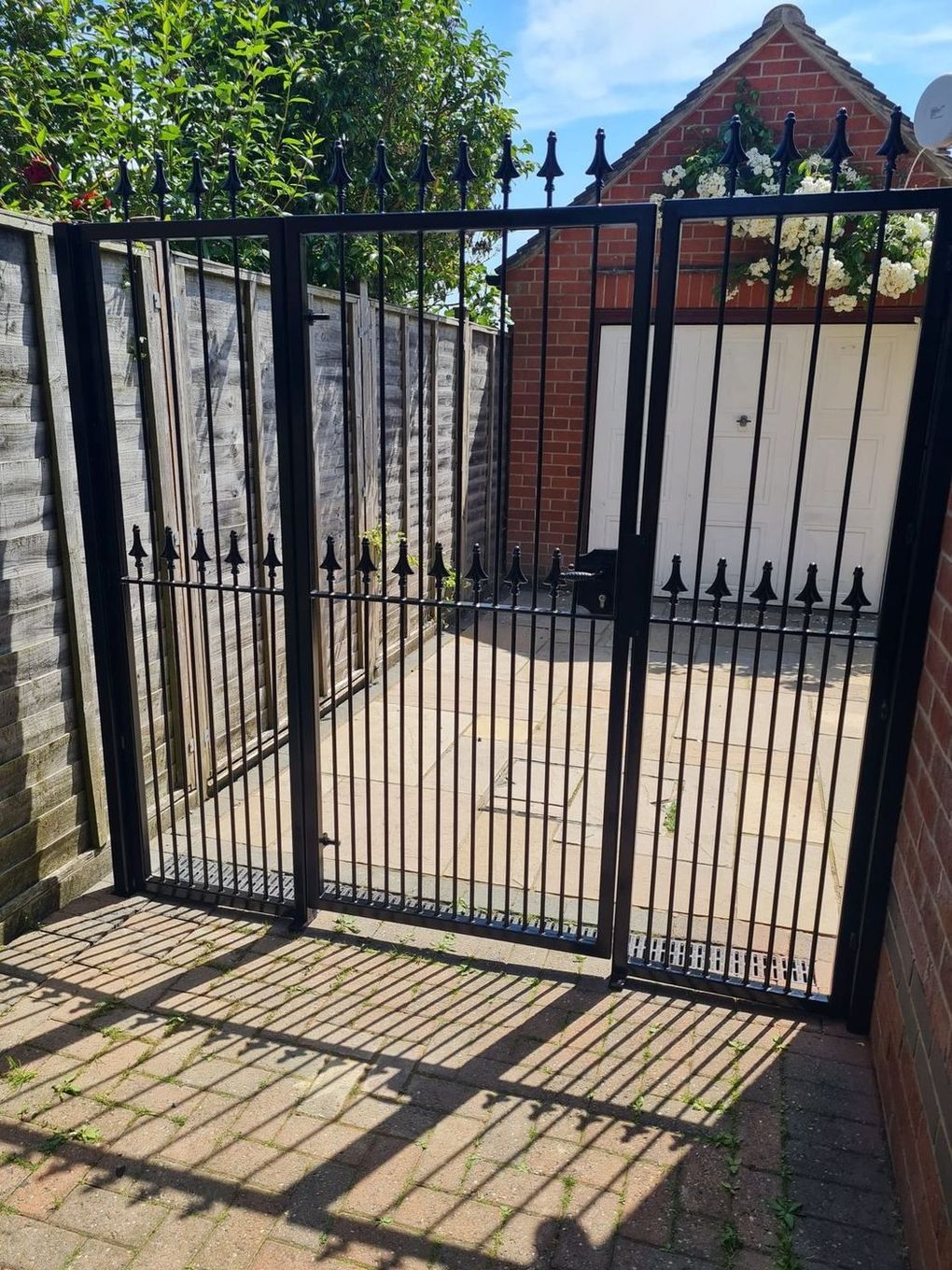 Traditional black spear-top metal gates with dog bars in a courtyard entrance