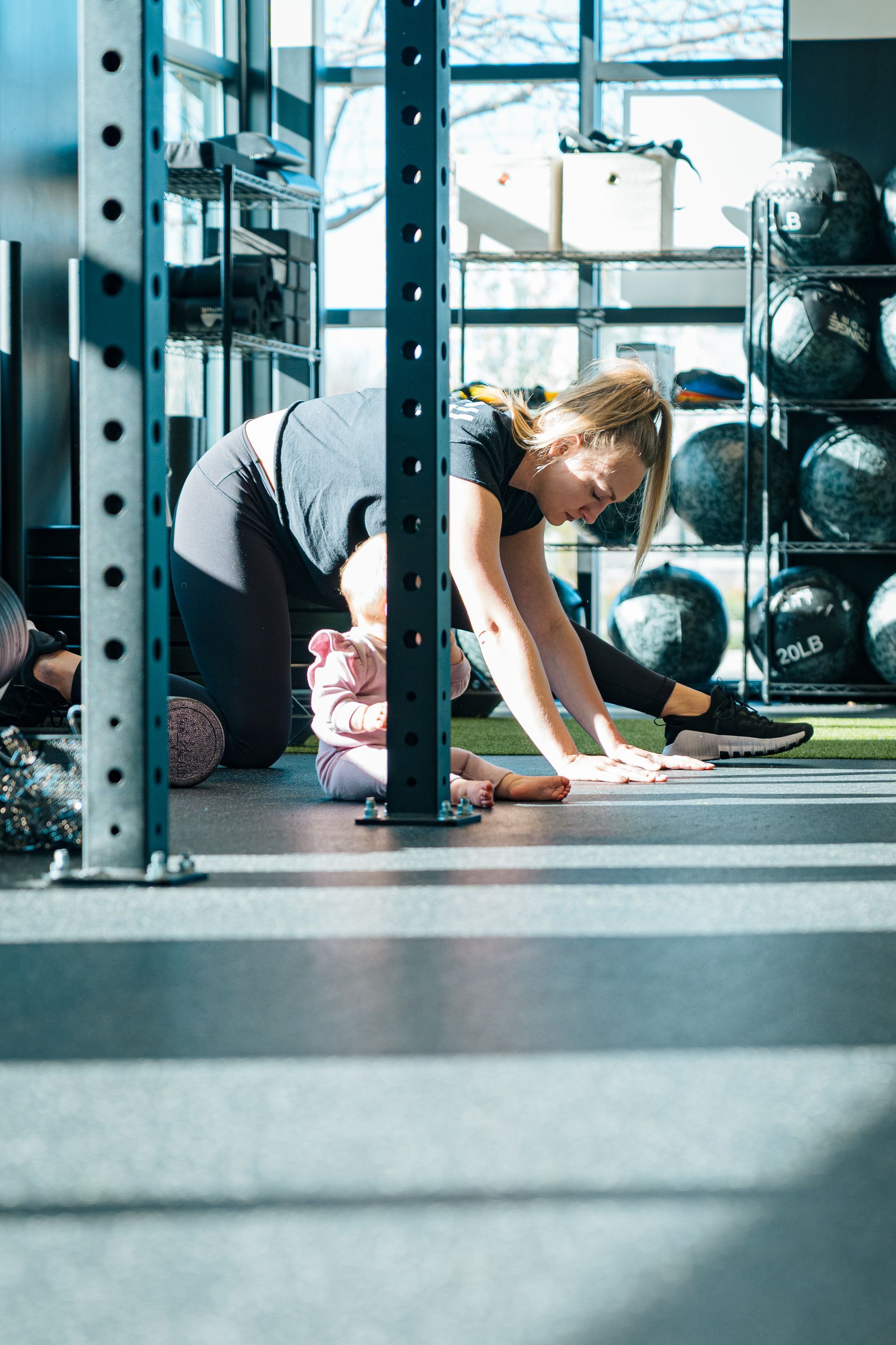 Woman in gym lifting a heavy barbell, preparing to deadlift.