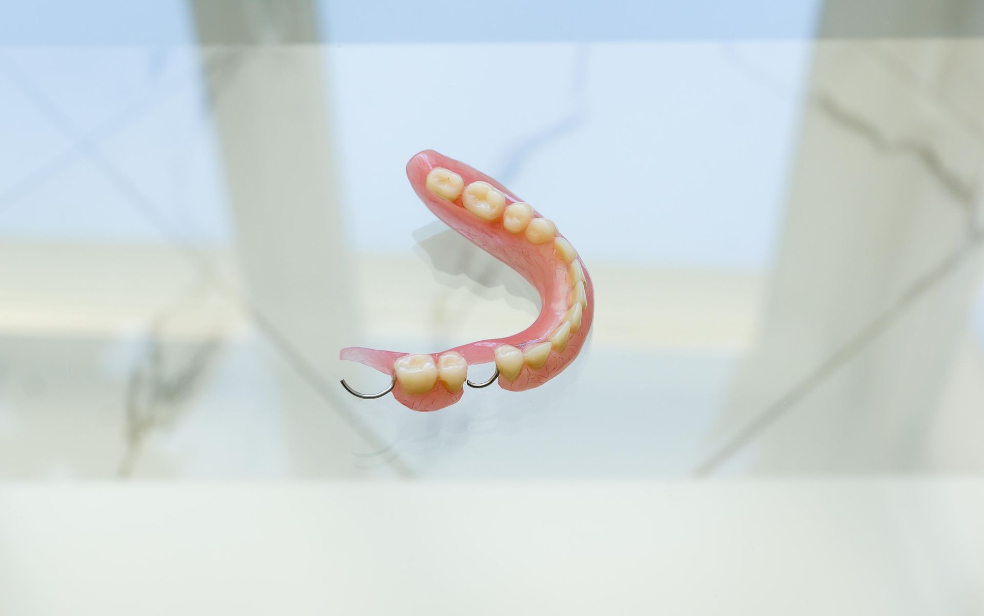 A denture is sitting on a glass table in front of a window.