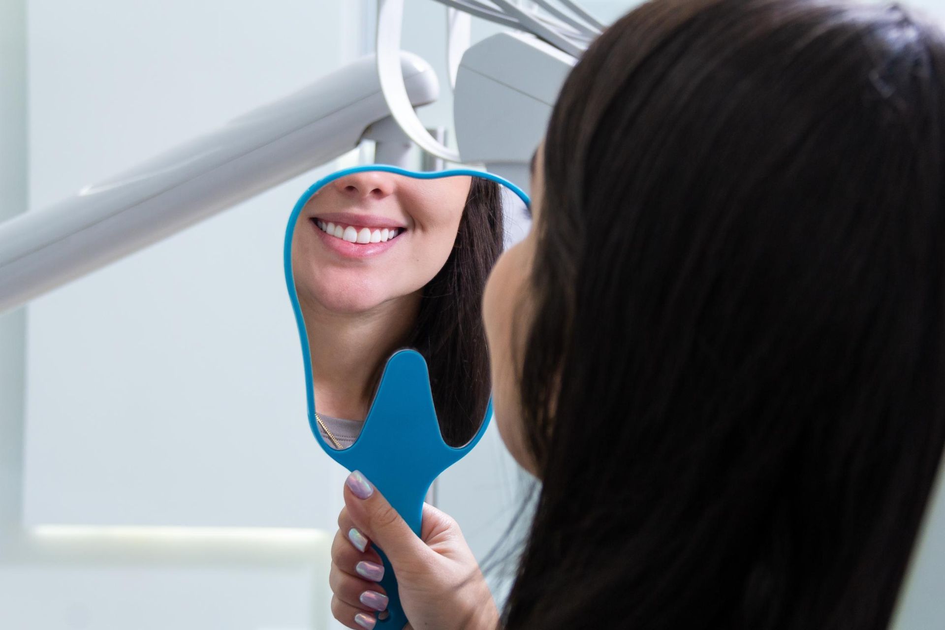 A woman is looking at her smile in a mirror.