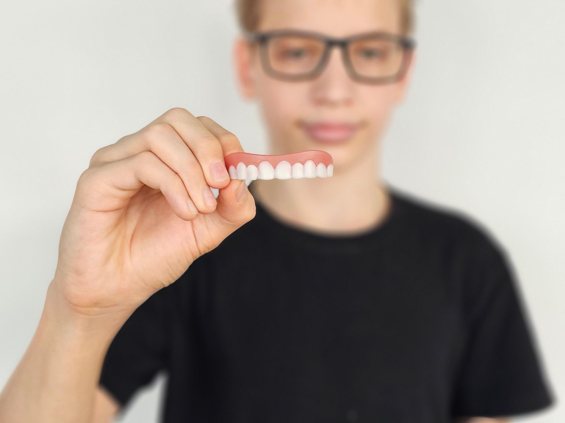 A dentist is holding a model of teeth and a pen.
