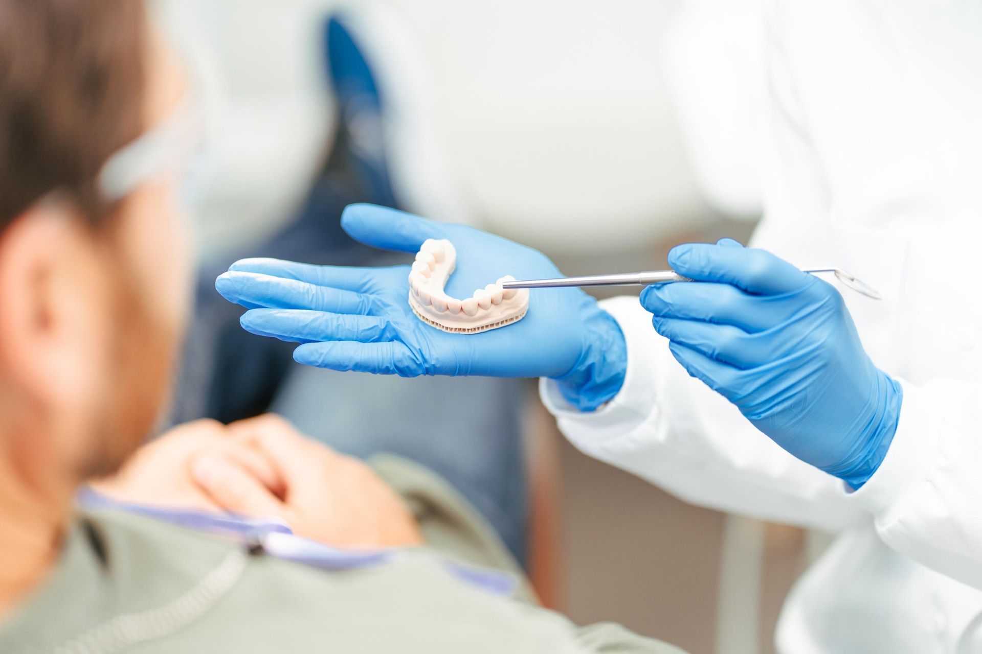 A dentist is holding a model of a man's teeth in her hand.