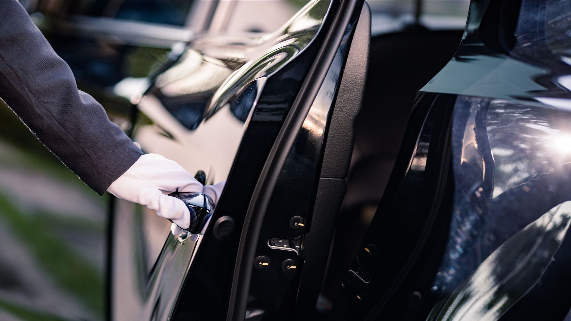A person is opening the door of a black car.