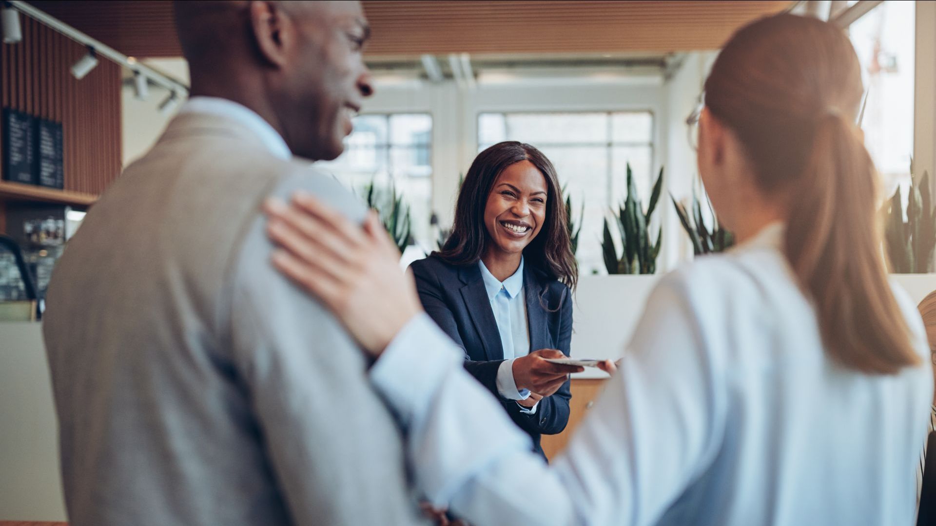 A woman is giving a credit card to a man and woman in a hotel lobby.