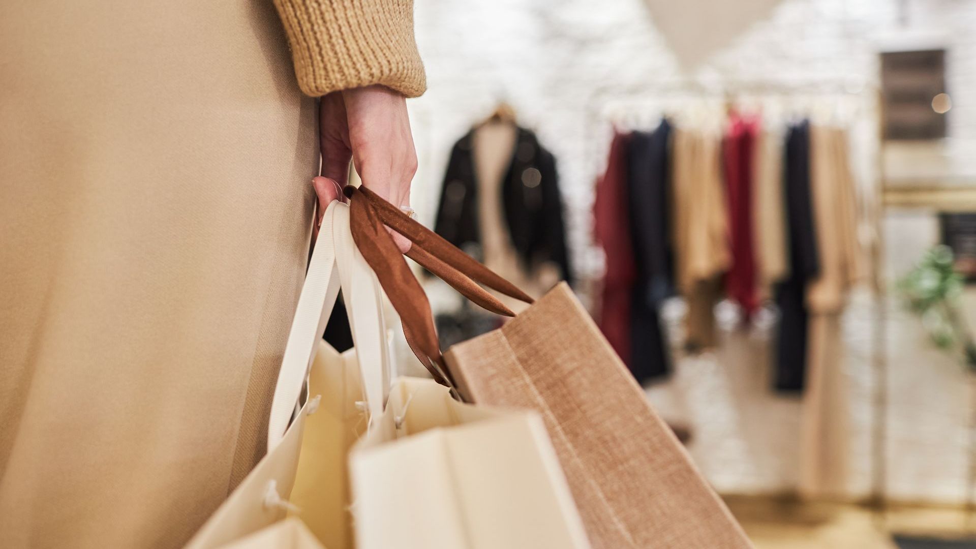 A woman is holding shopping bags in a clothing store.