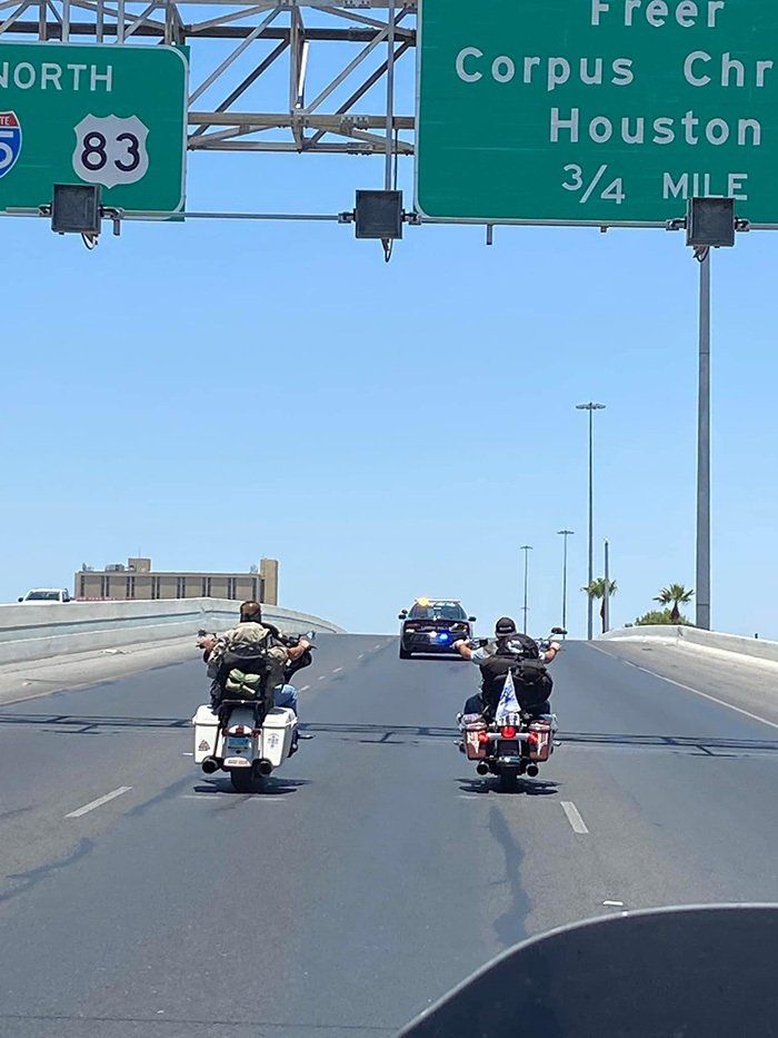 motorcyclists riding under road signs