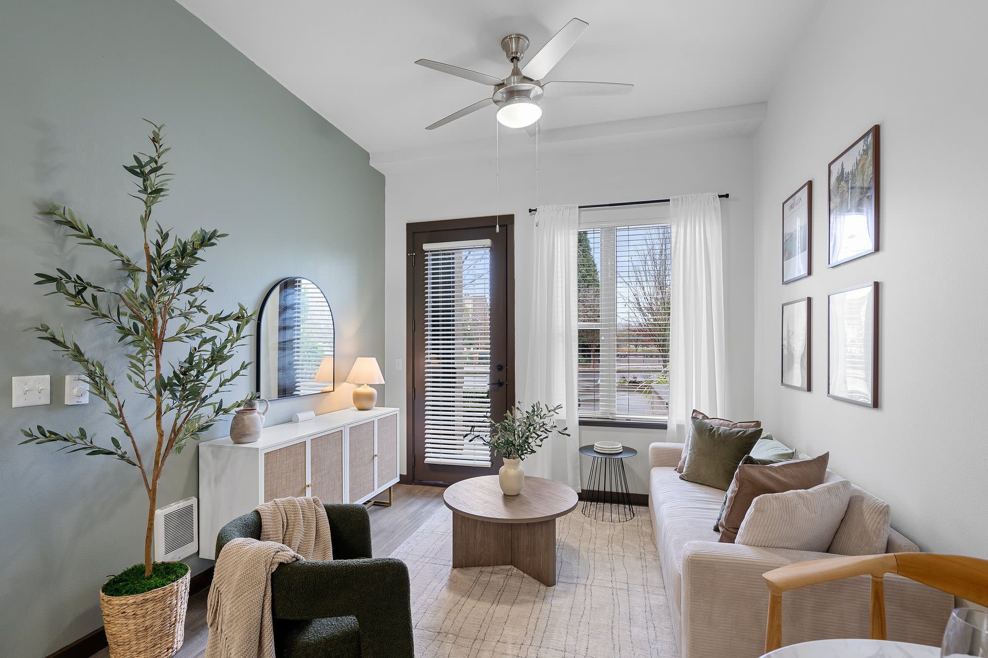 Living room in an apartment with a green accent wall, sofa, coffee table, and plants at Tessera at Orenco Station.
