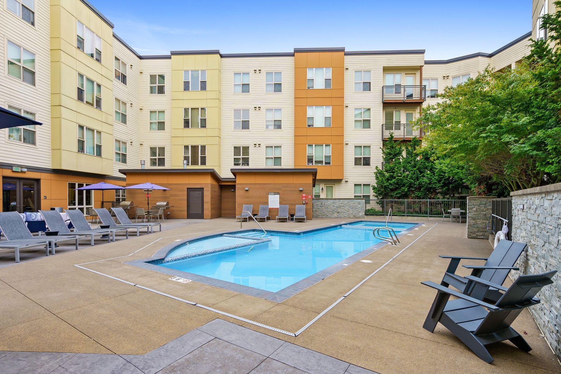 Outdoor apartment pool with lounge chairs and umbrellas in a courtyardat Tessera at Orenco Station.