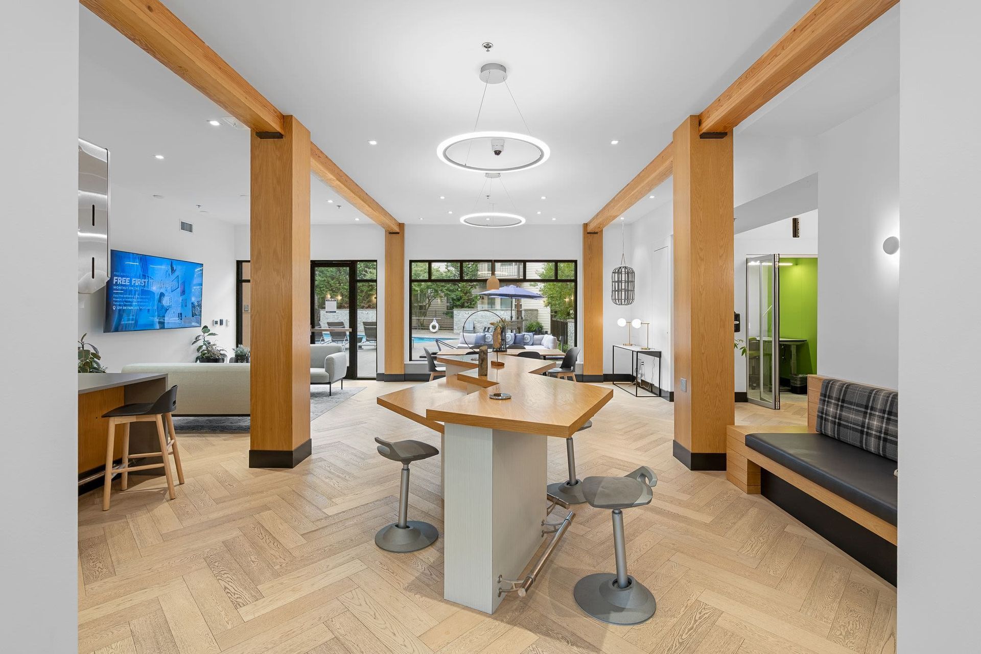 Interior community lounge with a large central wooden table, modern seating, and warm wood beamsat Tessera at Orenco Station.