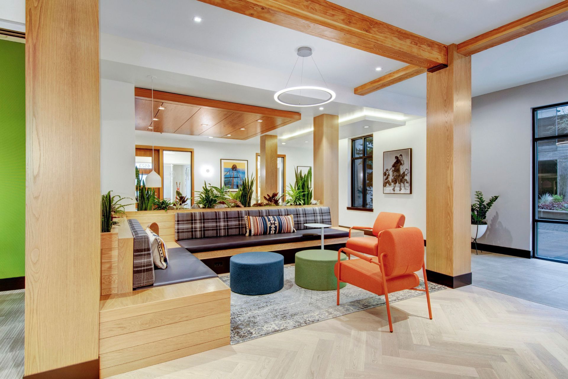Modern apartment community lounge with wooden beams, plants, and colorful seating at Tessera at Orenco Station.