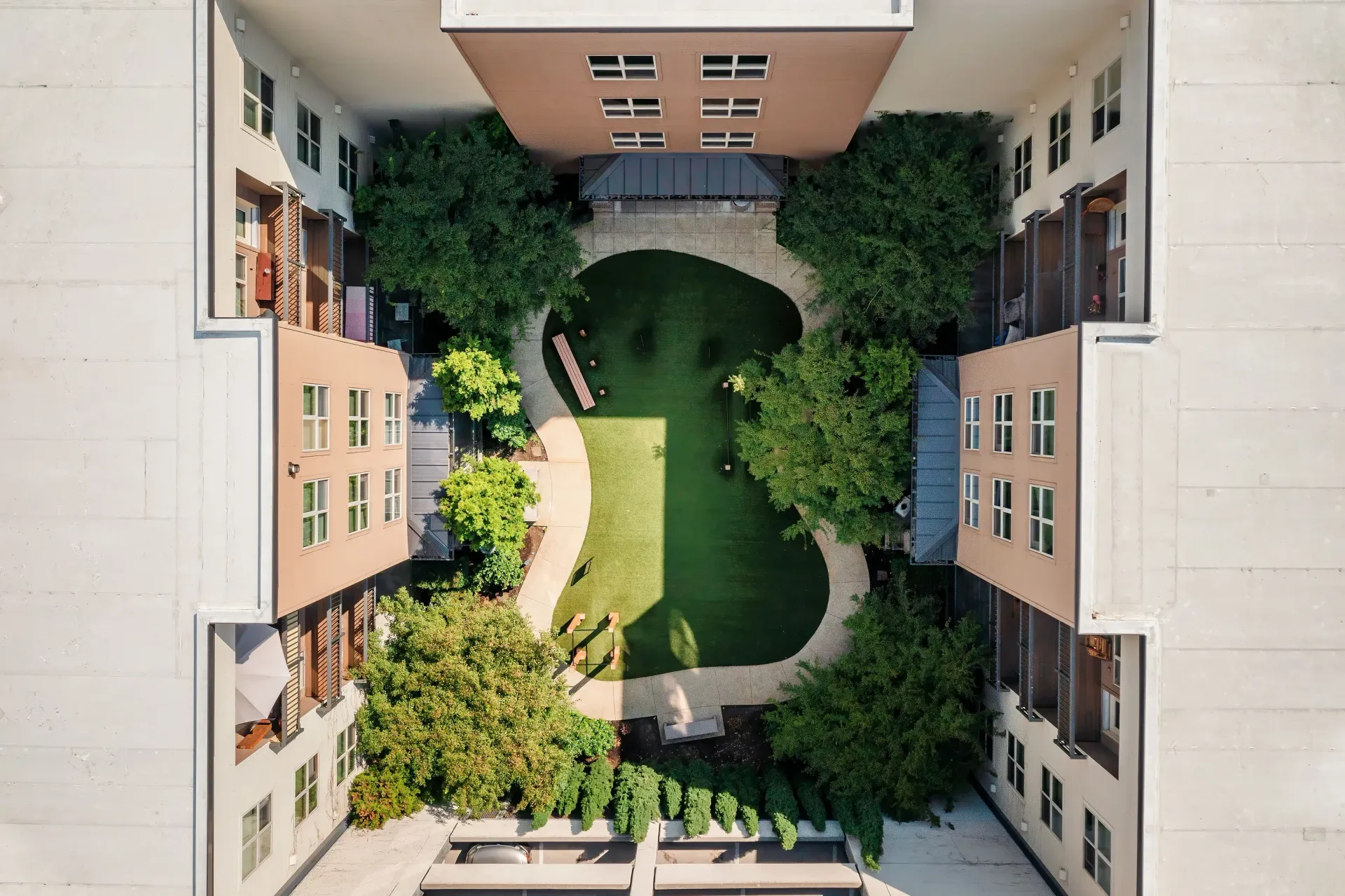 Aerial view of a courtyard between apartment buildings with trees and a green lawn at Tessera at Orenco Station.
