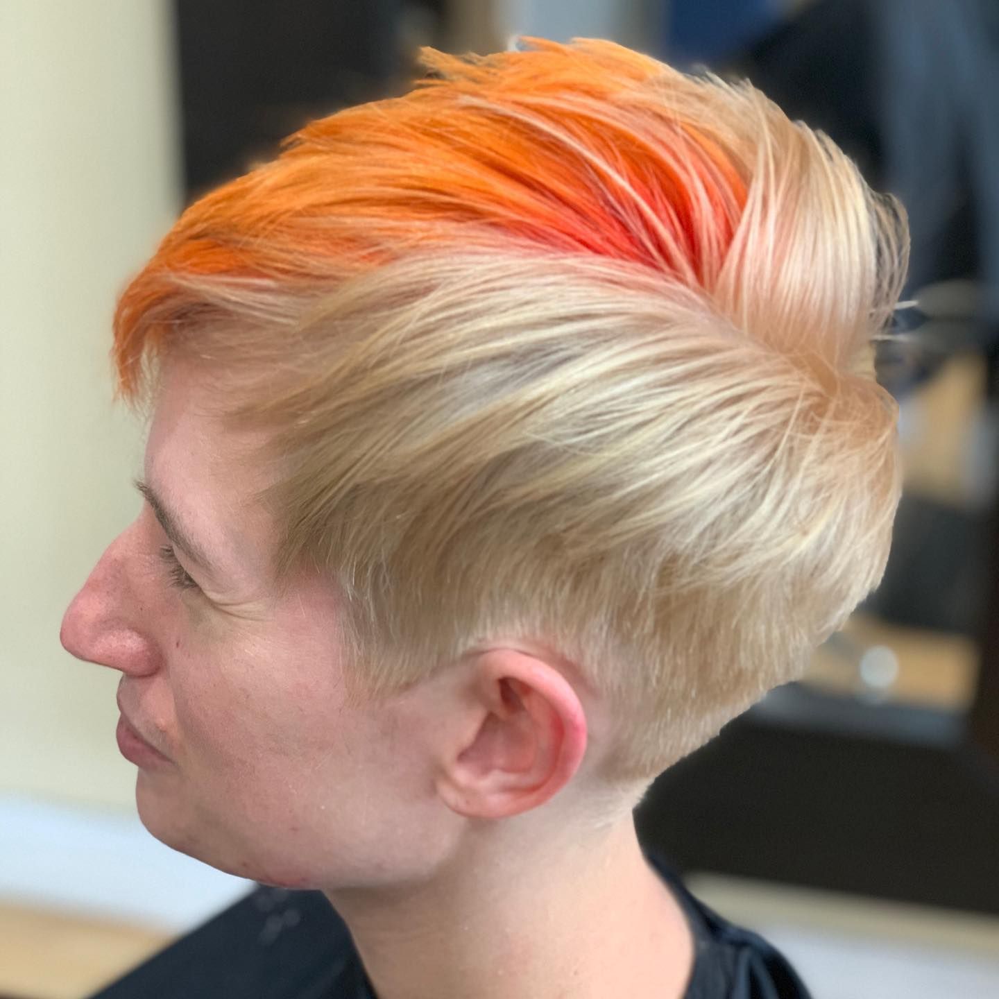 A woman with blonde and orange hair is sitting in a chair.