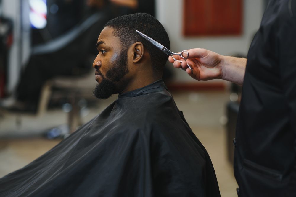 A man is getting his hair cut by a barber in a barber shop.