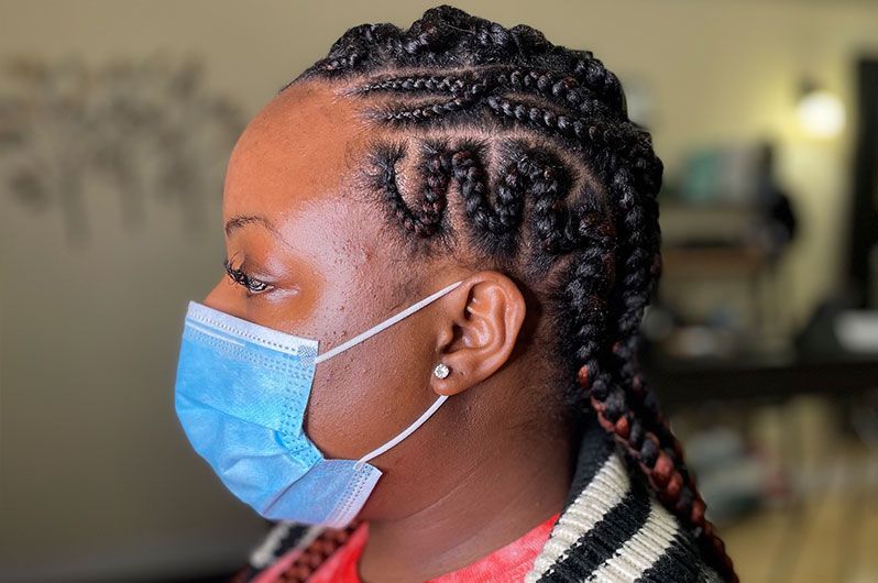 A woman with braids is wearing a blue face mask.