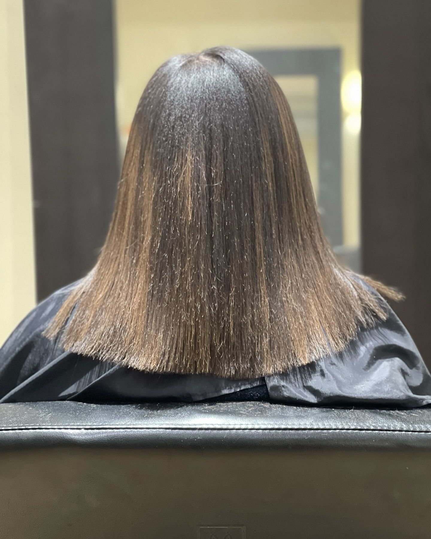 A woman with long hair is sitting in a chair at a hair salon.
