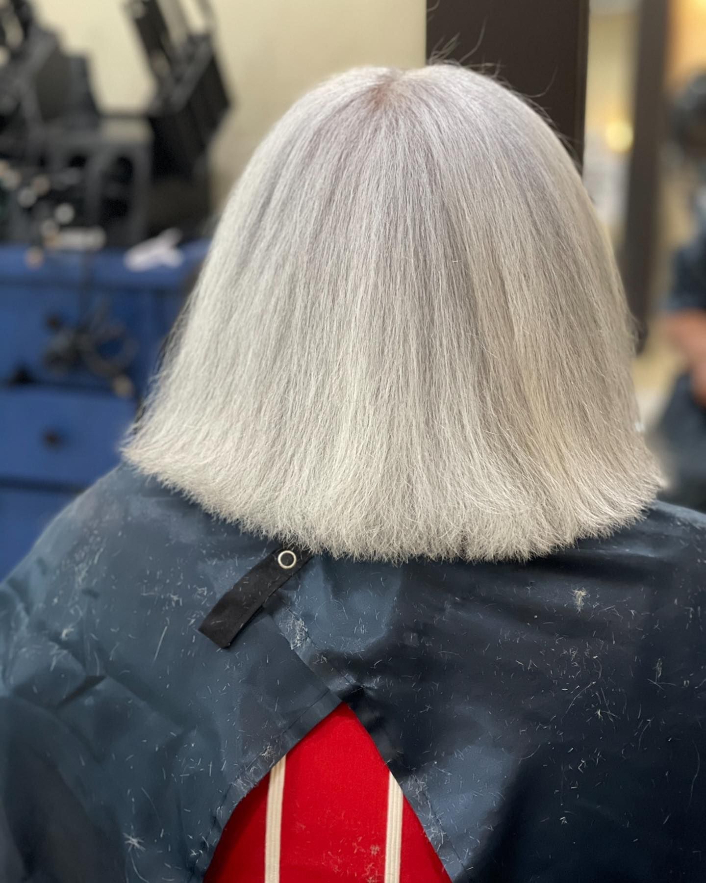 A woman with white hair is getting her hair cut in a salon.