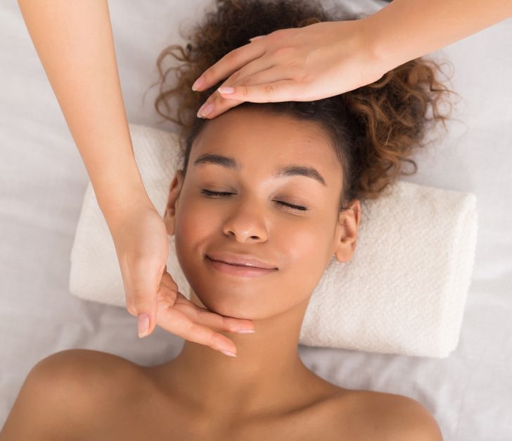 A woman is getting a facial massage at a spa.