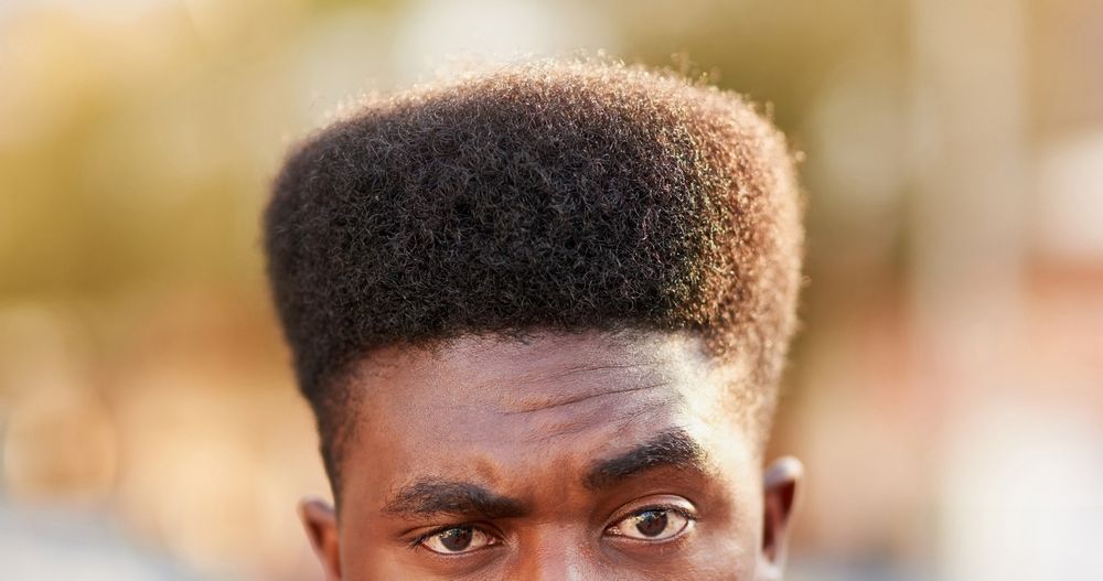 A close up of a man 's face with a high top hairstyle.