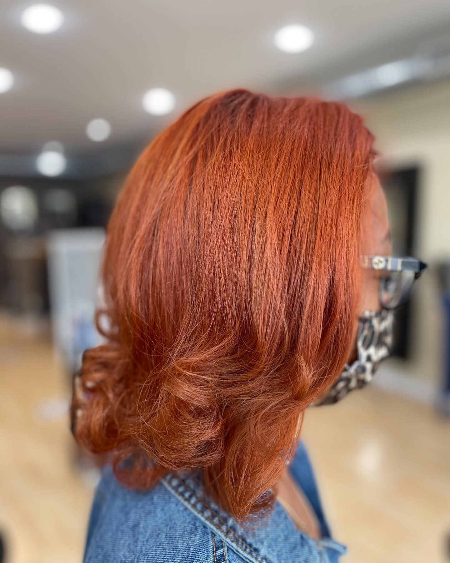 A woman with red hair and glasses is wearing a mask.