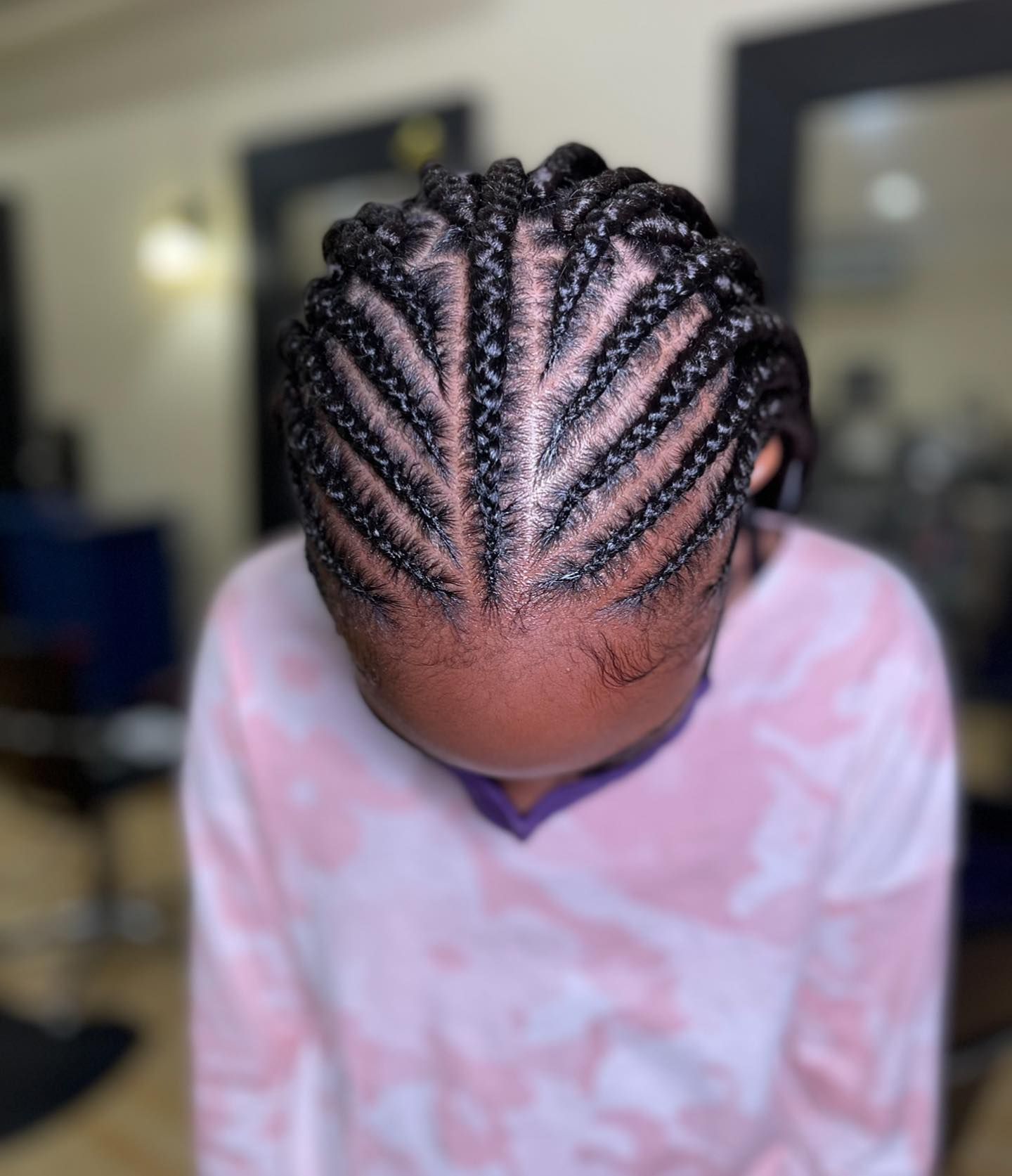 A girl with braids in her hair is wearing a pink shirt