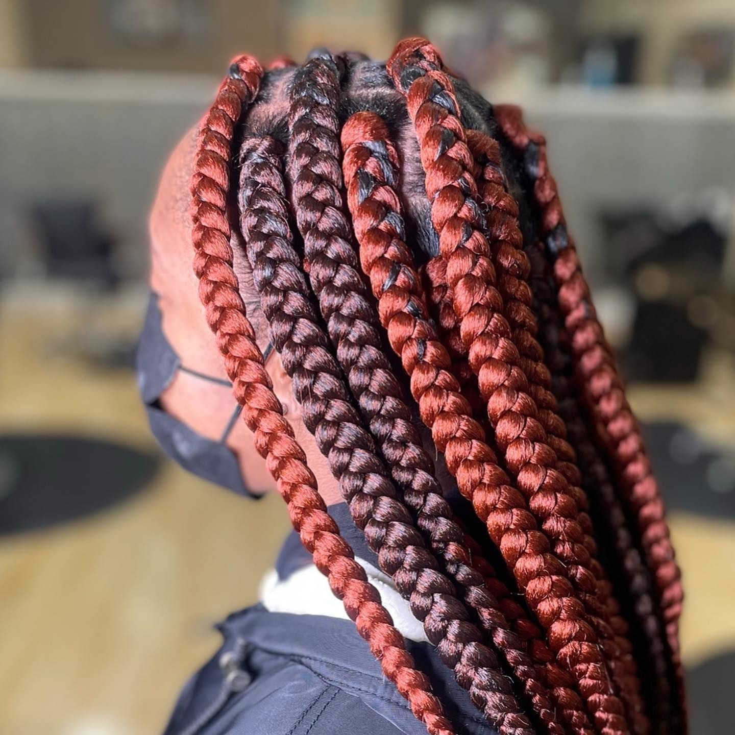 A woman wearing a mask has red braids in her hair.