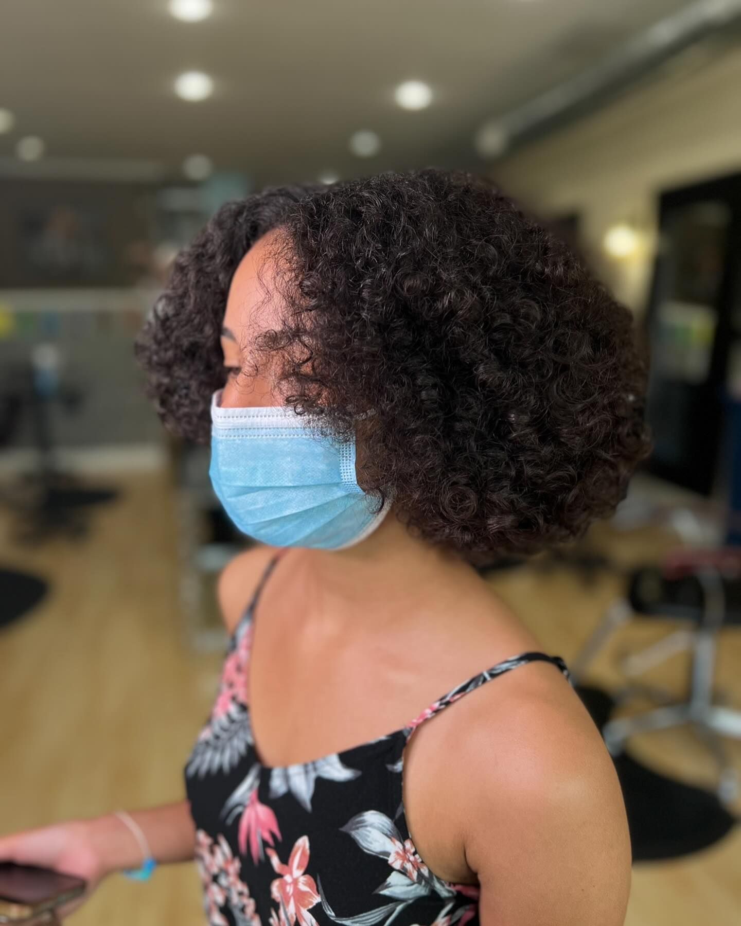 A woman with curly hair wearing a face mask