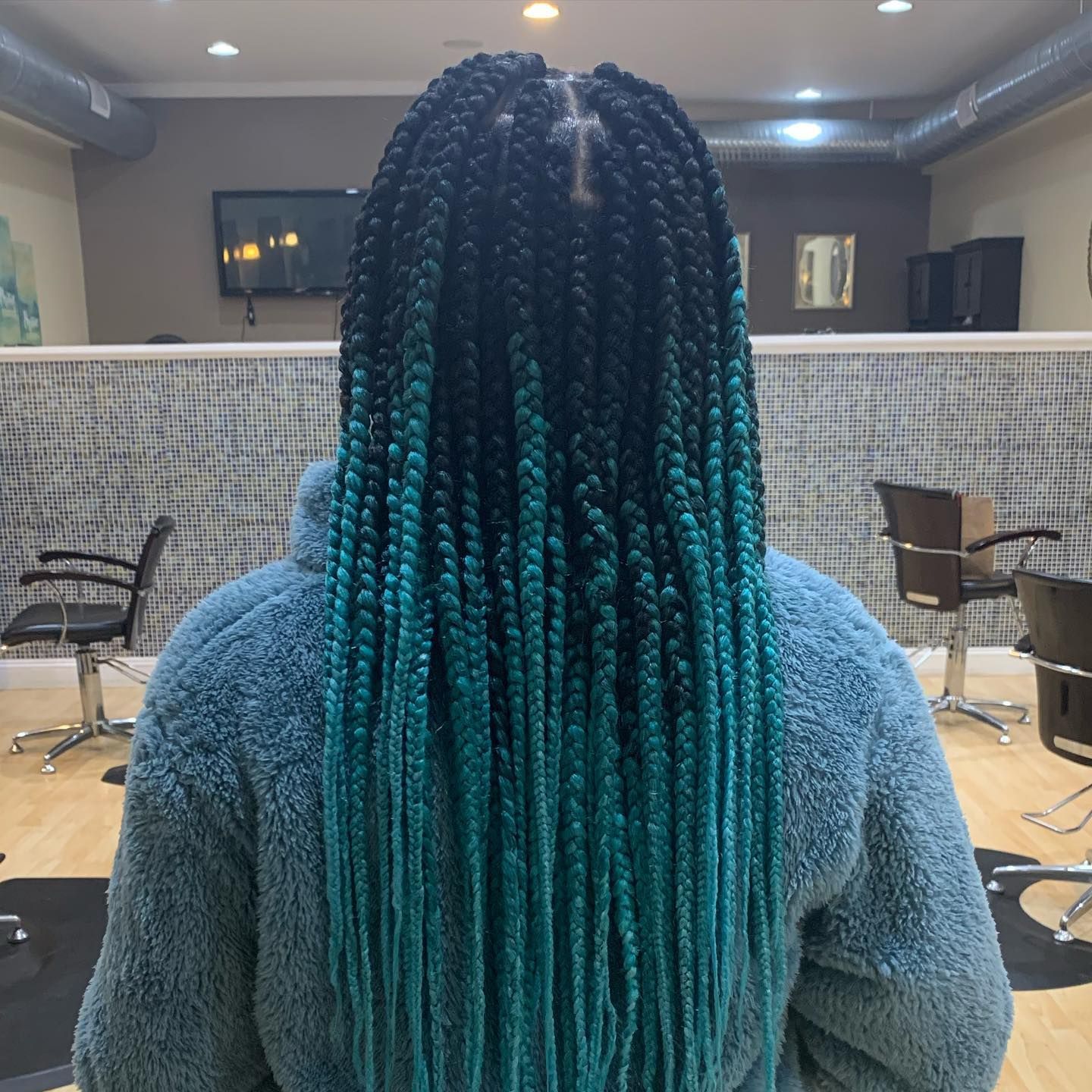 A woman with blue braids is wearing a blue jacket