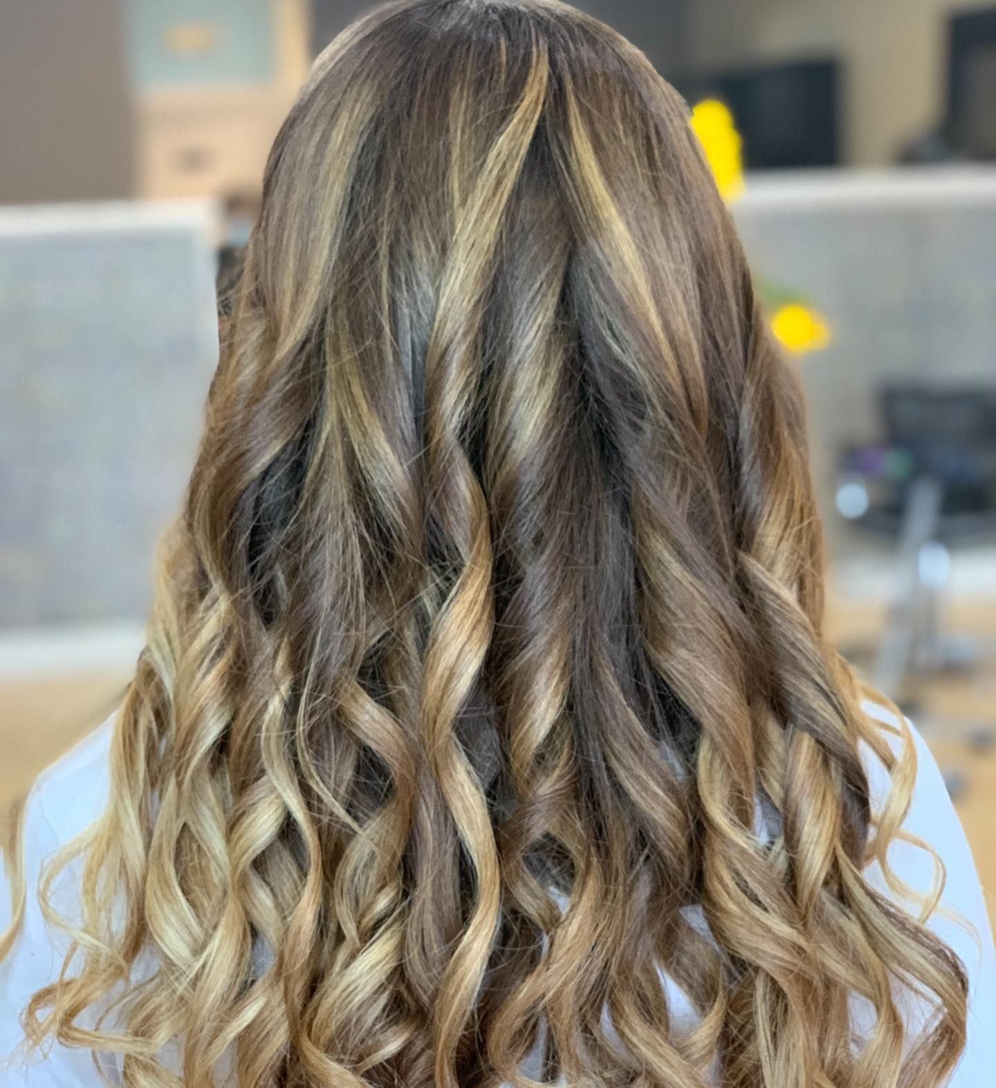 A woman with long curly hair is wearing a white shirt.