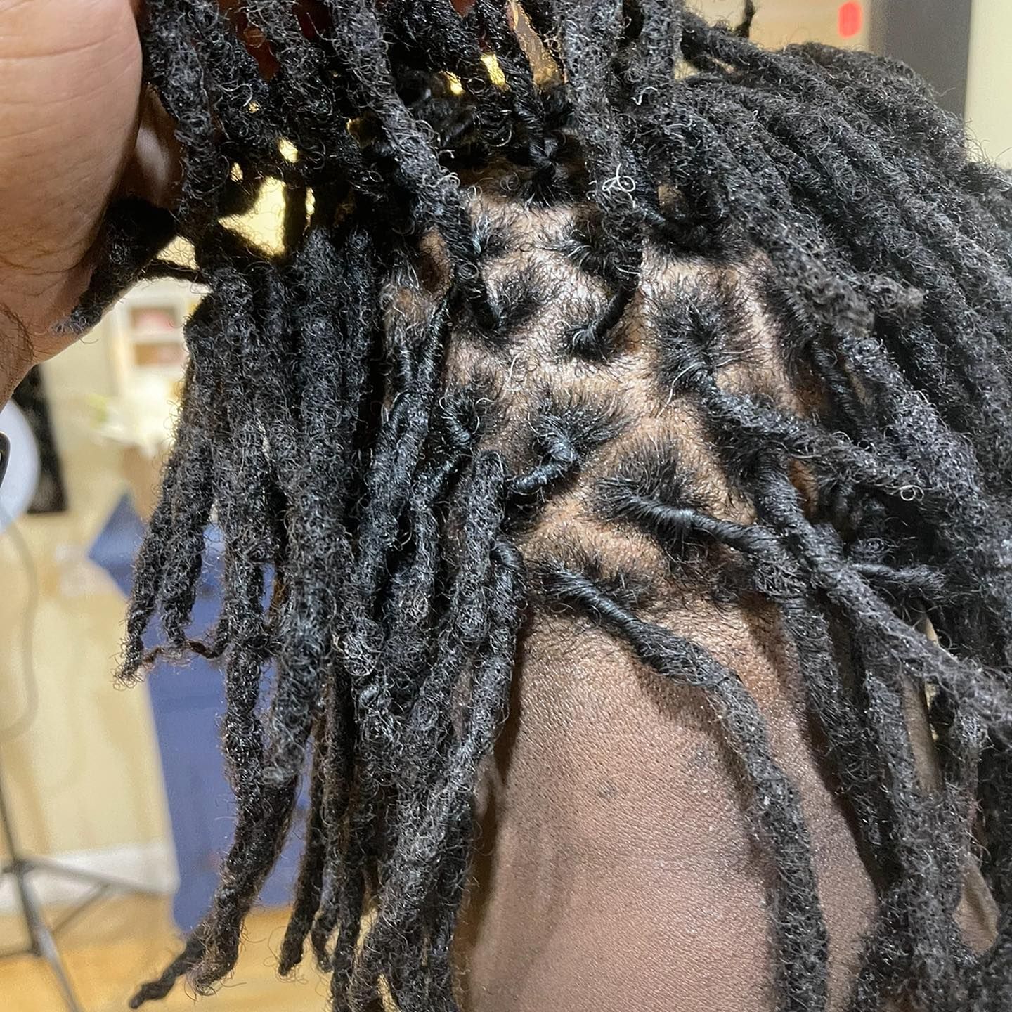 A person is holding a wig with dreadlocks on it.