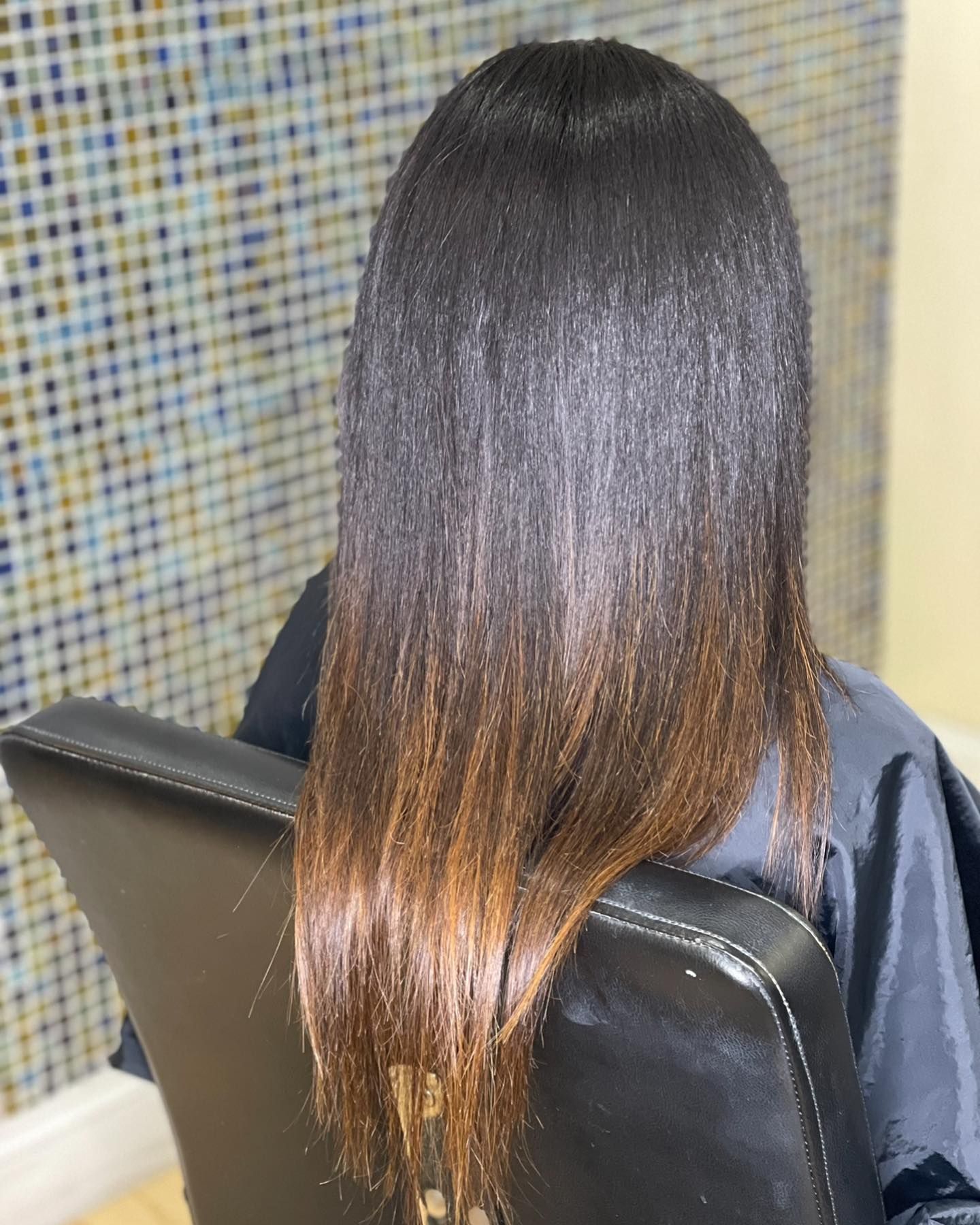 A woman with long black hair is sitting in a chair.