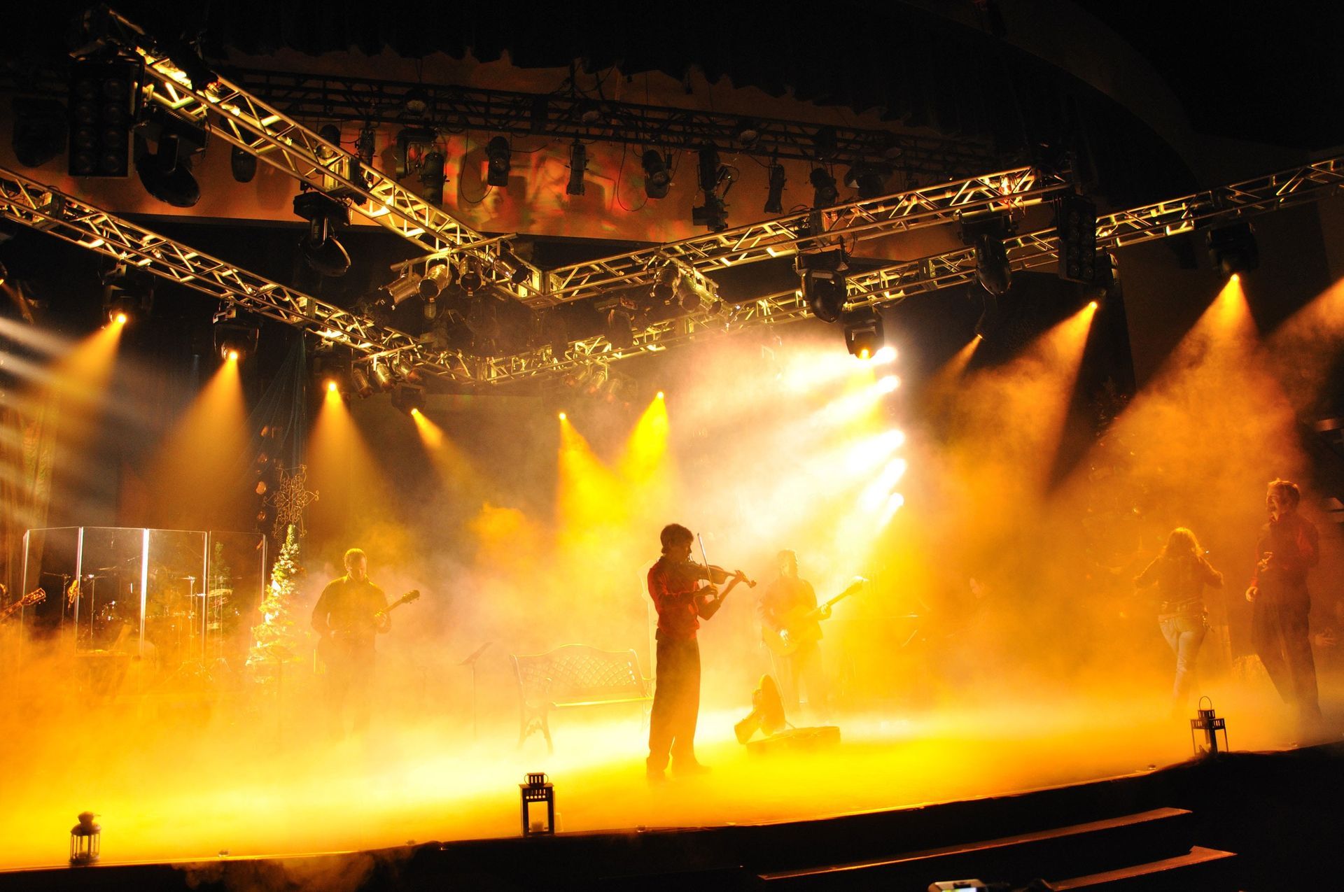 Singer on a brightly lit concert stage amid orange smoke and spotlights
