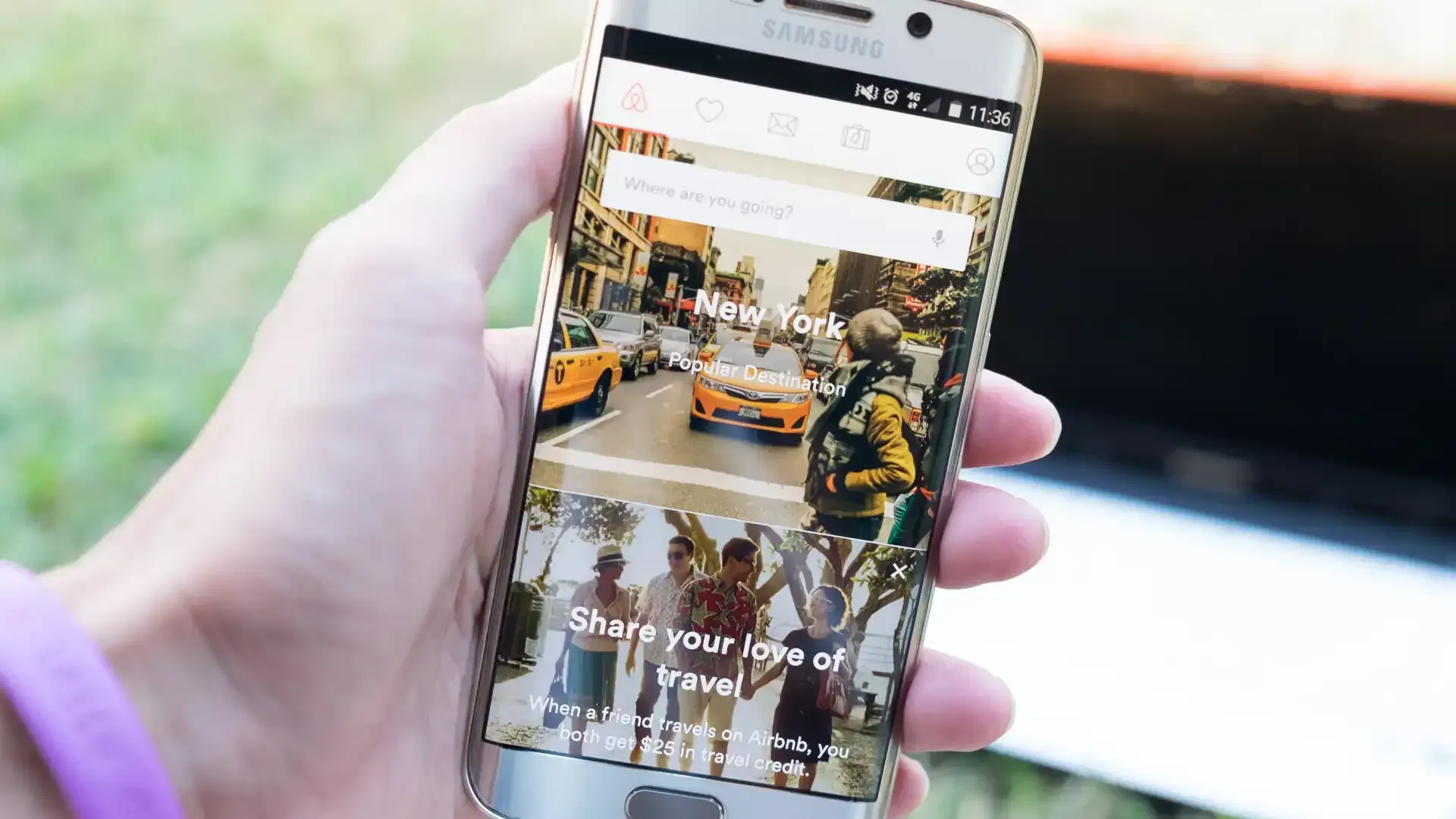 man holding mobile phone with screenshot of online platform for short-term rental accommodation worldwide