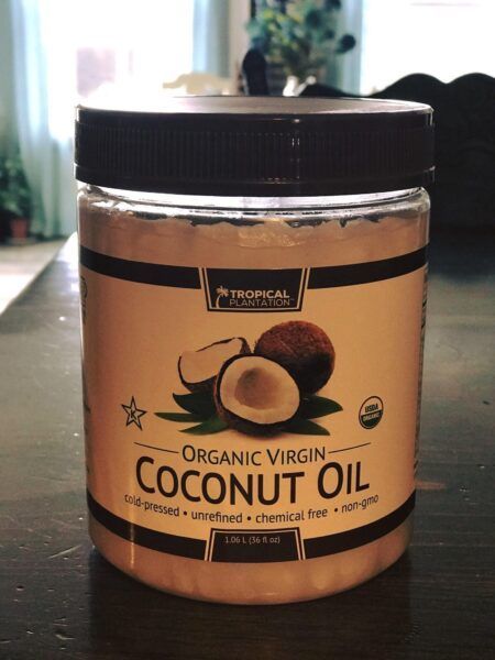 Large branded jar of coconut oil sitting on a wooden countertop.