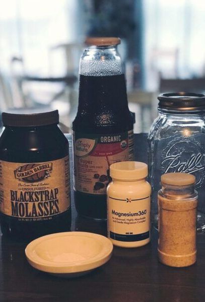 Blackstrap, organic non-concentrated fruit juice, magnesium, mineral salt, canning jar, mortar arranged on wooden counter.