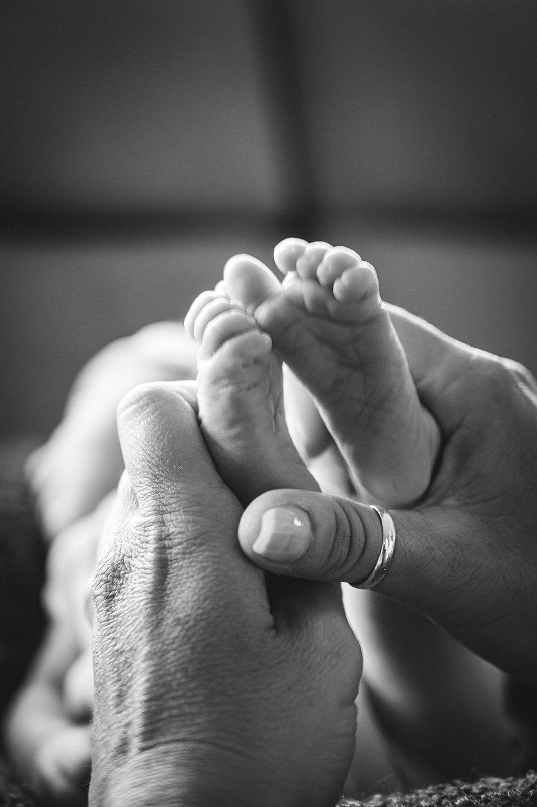 Manos adultas sosteniendo los pies de un recién nacido en un primer plano en blanco y negro