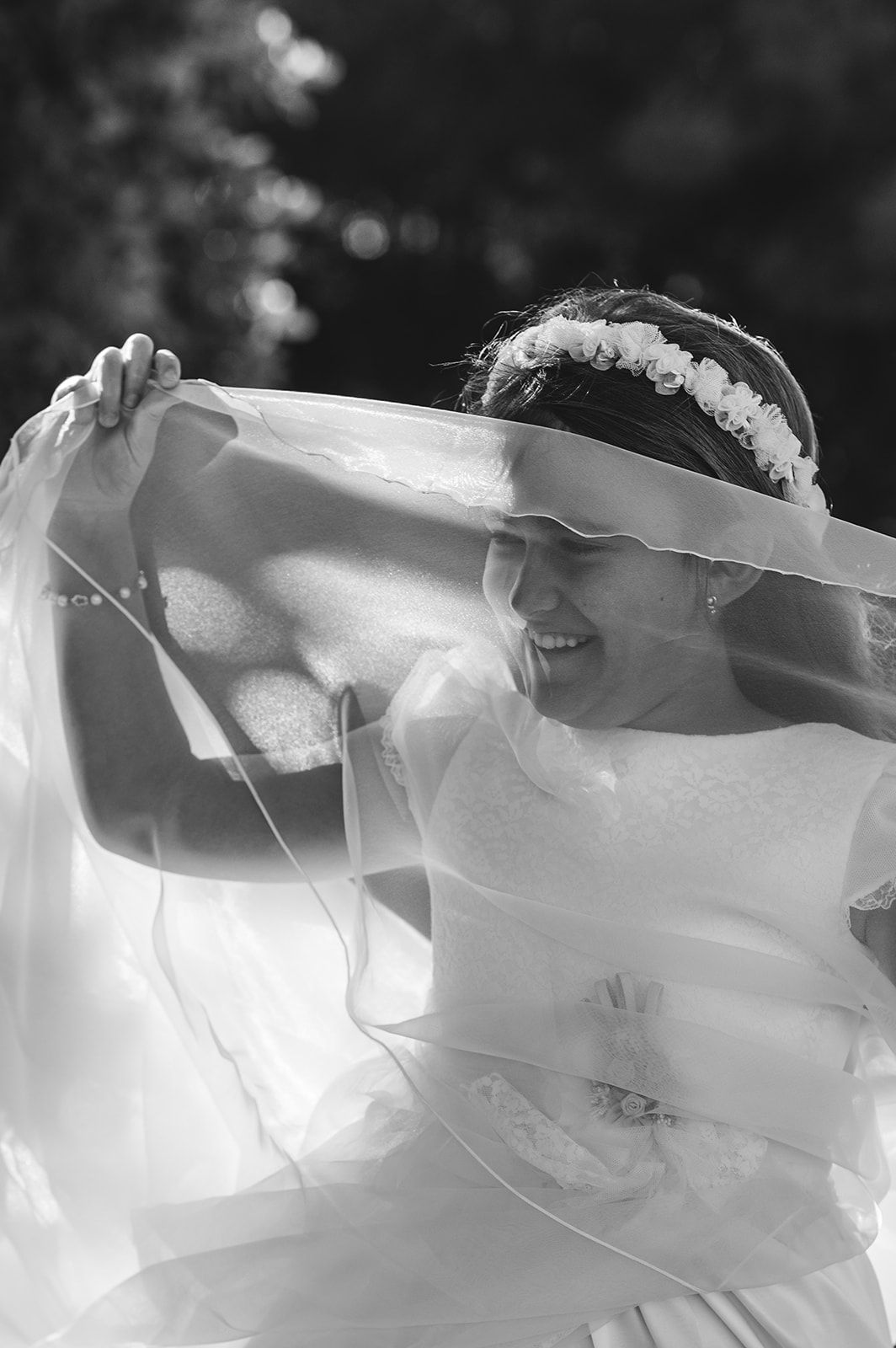 La novia levantándose el velo al aire libre, sonriendo bajo la luz intensa del sol