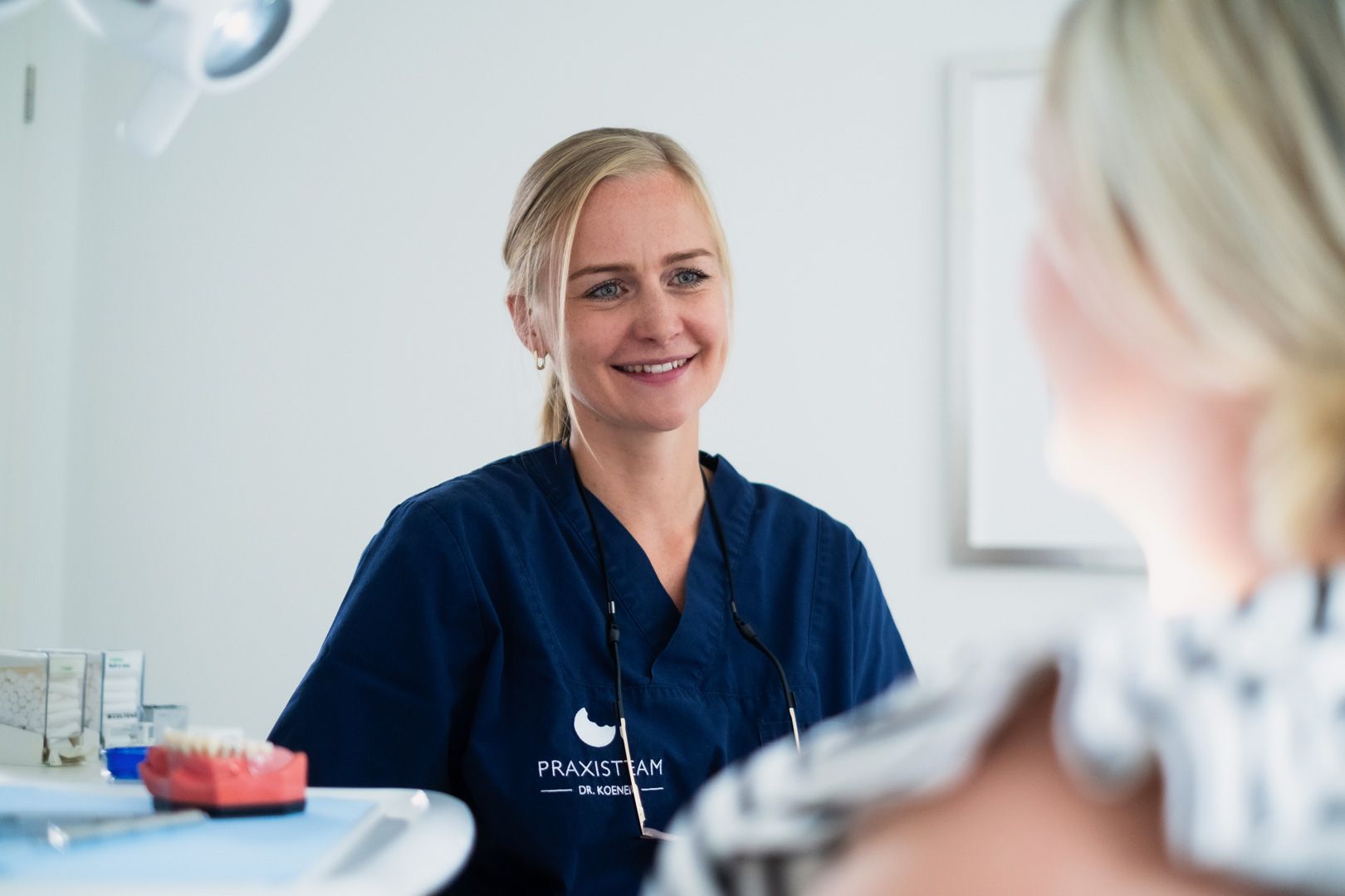 Eine Zahnärztin spricht in einer Zahnarztpraxis mit einem Patienten.