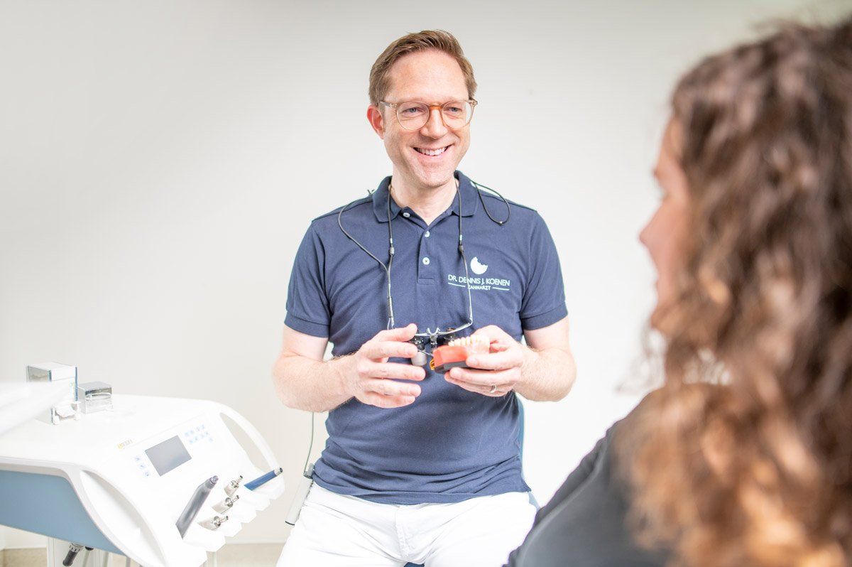 Ein Zahnarzt spricht in einer Zahnarztpraxis mit einem Patienten.