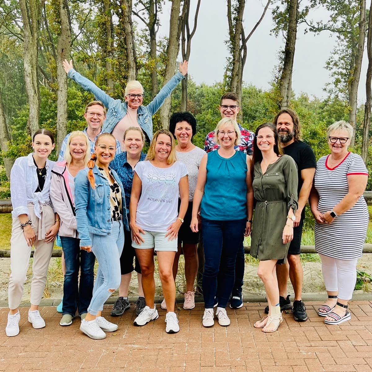Eine Gruppe von Menschen posiert vor Bäumen für ein Foto.