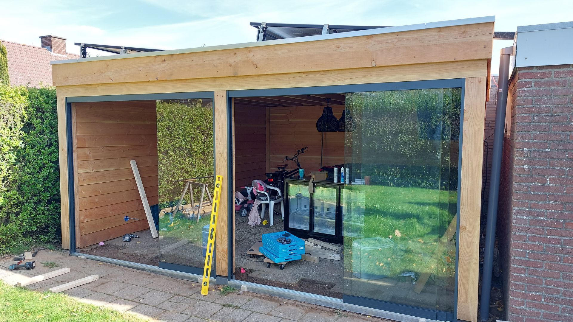Een moderne schuur met grote glazen schuifdeuren en een lichte houten buitenkant. | Smans Houtbouw