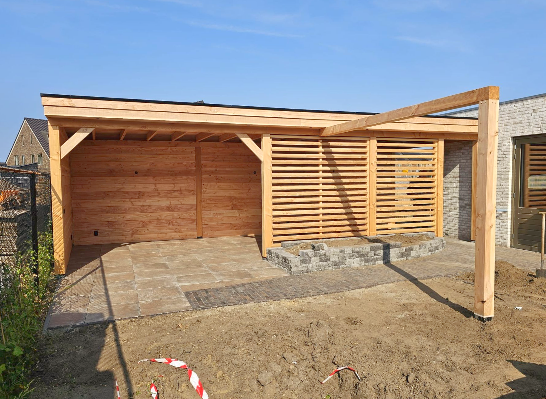 Houten pergola en schuurconstructie in een zonnige buitenomgeving met een voorgrond van aarde.